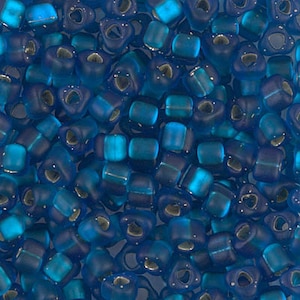 May include: A close-up of a pile of blue glass seed beads with a frosted finish. The beads have a heart-shaped hole in the center.