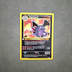 May include: A Charizard trading card featuring a purple dragon-like creature breathing fire. The card displays 120 HP, the Energy Burn Pokemon Power, and the Fire Spin attack. It includes text detailing the creature's length of 5'7" and weight of 200 lbs.