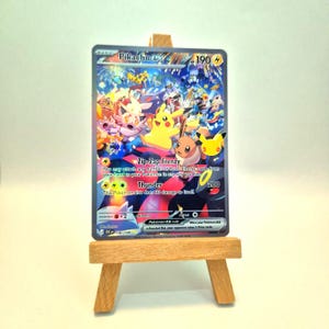 Puede incluir: Una carta coleccionable Pikachu EX con una colorida ilustración de varios personajes Pokemon, incluyendo Pikachu, Eevee y Umbreon. La carta muestra el texto Pikachu EX, 190 HP, Zip-Zap Frenzy y Thunder, apoyada sobre un pequeño caballete de madera.