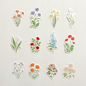May include: Twelve different flower stickers with white backgrounds. The flowers are in various colors, including red, orange, yellow, blue, purple, and pink. The flowers are arranged in a grid pattern.