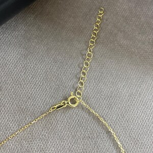 May include: A gold-toned metal necklace chain featuring a delicate link design, a circular spring ring clasp, and an attached extender chain with larger circular links for adjustable length, showcasing a polished metallic finish throughout.
