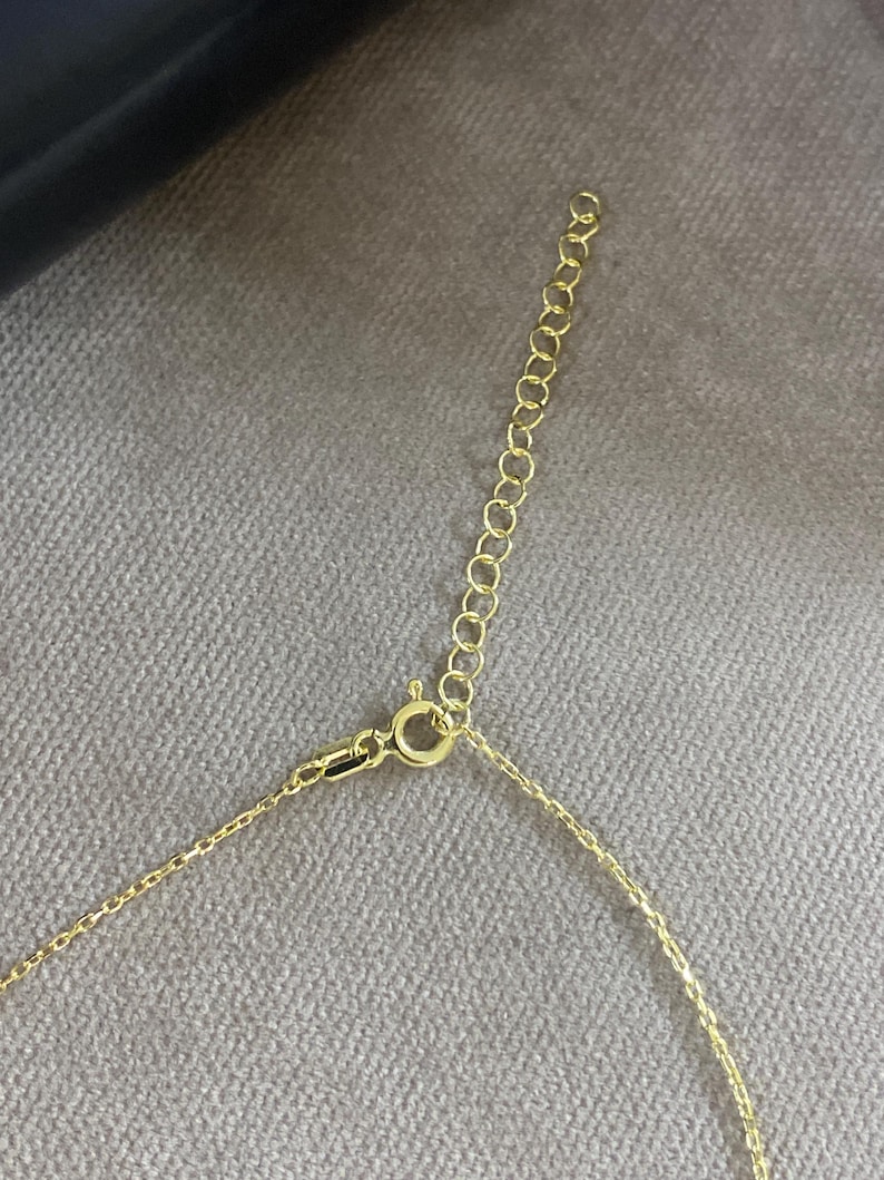 May include: A gold-toned metal necklace chain featuring a delicate link design, a circular spring ring clasp, and an attached extender chain with larger circular links for adjustable length, showcasing a polished metallic finish throughout.