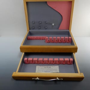May include: Wooden silverware storage box with two pull-out trays. The interior features a gray lining with pink velvet dividers for utensils. The box has a silver handle and a small label with text.