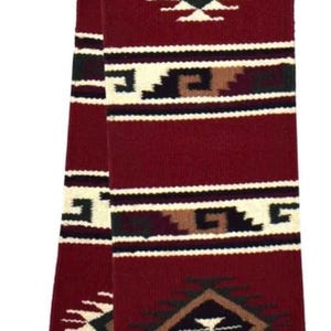 May include: A long, rectangular woven scarf in deep burgundy featuring a repeating geometric pattern. The design includes horizontal bands of cream, black, and brown, with central diamond motifs and fringed ends at the bottom edge.