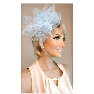 May include: A light blue headpiece with a floral design, feathers, and pearl accents. The headpiece is worn on the head. The woman is wearing a peach-colored sleeveless top.