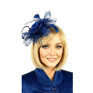 May include: A navy blue fascinator with a floral design. The headpiece features a large, layered flower with feathers and netting accents. The accessory is worn on the side of the head and is suitable for special occasions.