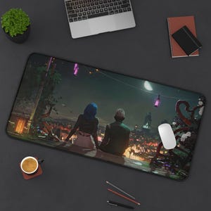 May include: A black and white mouse mat featuring a cityscape with two figures in the foreground. The figures are silhouetted against a moonlit sky with purple lights strung across the scene.