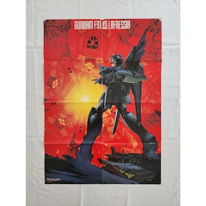 Puede incluir: Póster plegado con un robot Gundam en una pose dinámica sobre un fondo rojo y amarillo. El texto "GUNDAM F91 VS LAFRESSIA" se muestra en la parte superior. El póster tiene una estética vintage.