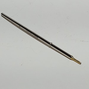 Pode incluir: Uma recarga de caneta de prata com uma ponta dourada.