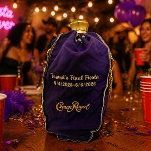 May include: A purple fabric Crown Royal bottle bag featuring gold embroidered text that reads Tammi's Final Fiesta 6/4/2026-6/6/2026 and the Crown Royal logo. The bag has a gold drawstring closure at the top and sits on a wooden surface.
