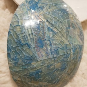 May include: A blue and white mosaic bowl with a cracked and iridescent finish. The bowl is round and has a smooth, glossy surface.
