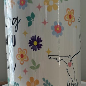 Pode incluir: Caneca de cer&acirc;mica branca decorada com flores coloridas, estrelas e folhas. A caneca apresenta o texto "Missing You" e um contorno do estado da Fl&oacute;rida com um cora&ccedil;&atilde;o. O nome "Wendy" tamb&eacute;m &eacute; exibido.