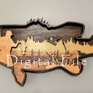 May include: Wooden layered art piece in the shape of a fish, featuring a fisherman and a landscape scene. The piece is made of various shades of brown wood, with the text "Digital File" overlaid on the image.