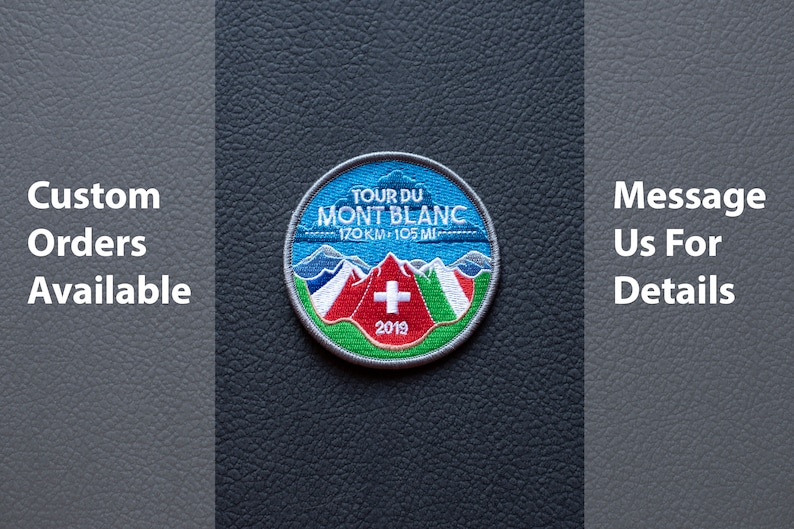 May include: Circular embroidered patch with the text "TOUR DU MONT BLANC 170 KM - 105 MI", featuring a mountain range, a Swiss flag, and the year 2019. The patch has a blue, white, red, and green colour scheme. The text "Custom Orders Available" and "Message Us For Details" are also present.
