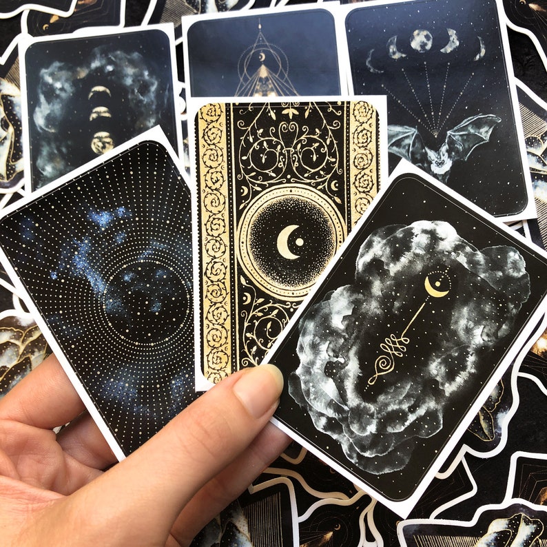 May include: A set of ten black and gold stickers with celestial and moon designs. The stickers feature intricate patterns, stars, and moons.