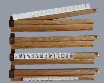 May include: Wooden Mahjong tile racks with white tiles. The racks are made of light brown wood and have a slot to hold the tiles. Some racks are open, displaying the tiles with red and black symbols.
