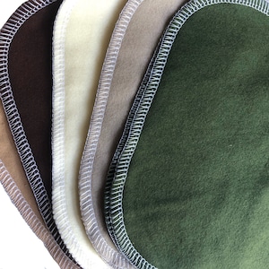 May include: Five fabric squares with white stitching around the edges. The squares are in shades of brown, beige, cream, and green.