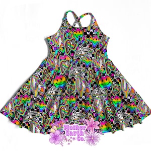 May include: A sleeveless dress with a black background and a colorful, psychedelic pattern. The pattern includes smiley faces, ghosts, and mushrooms in rainbow colors. The dress has a criss-cross back and a flared skirt.