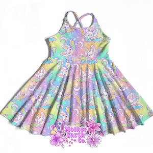 May include: A pastel-colored dress with a bat pattern. The dress features a halter neckline and a flared skirt. The bat pattern includes crescent moons and stars. The dress is decorated with the text "Mother Earth Co."