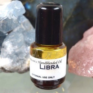 May include: A small glass bottle with a black cap filled with a golden liquid. The label reads "Handblended Oil LIBRA EXTERNAL USE ONLY".