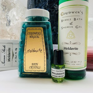 May include: A set of Moldavite bath and body products, including bath crystals, bubble bath and shower gel, and essential oil. The products are packaged in green bottles with gold labels and feature the text "Ceridwen's Magical" and "Moldavite".