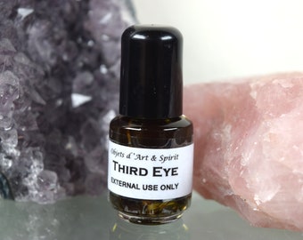 May include: A small glass bottle with a black cap filled with a brown liquid. The label reads "Objets d'Art & Spirit THIRD EYE EXTERNAL USE ONLY".