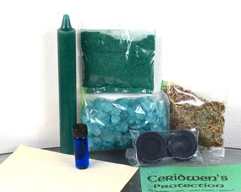 May include: A green candle, a small bottle of blue liquid, a bag of green crystals, a bag of green powder, a bag of dried herbs, two black charcoal discs, and a white card with the text "Ceridwen's Protection" in green lettering.