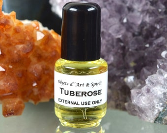 May include: A small glass bottle with a black cap filled with a yellow liquid. The label reads "Objets d'Art & Spirit, Tuberose, External Use Only".