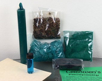 May include: A green candle, a small bottle of blue liquid, green bath crystals, green glitter, dried herbs, and two black charcoal discs are included in this prosperity spell kit. The kit is labelled "Ceridwen's Prosperity".