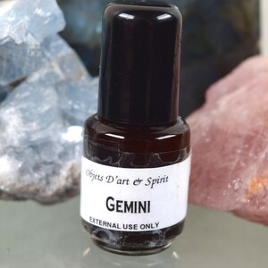 May include: A small brown glass bottle with a black cap and a white label that reads "Objets D'art & Spirit GEMINI EXTERNAL USE ONLY".