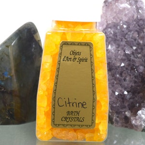 May include: A clear glass jar filled with yellow bath crystals. The jar has a gold label that reads "Objets d'Art & Spirit" and "Citrine Bath Crystals".