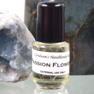 May include: A small clear glass bottle with a black cap. The bottle contains a light yellow liquid. The label on the bottle reads "Ceridwen's Handblended Oil Passion Flower External Use Only".