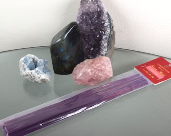 Può includere: Un pacchetto di bastoncini di incenso alla lavanda con un'etichetta rossa che dice "COWBOYS Lavender Incense Sticks". Il pacchetto è su una superficie di vetro con diversi cristalli, tra cui un grande ammasso di ametista, un quarzo rosa, una celestite blu e una labradorite nera.