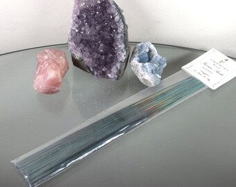 Può includere: Un pacchetto di bastoncini di incenso con un'etichetta bianca che recita "Garden's Gate Incense - Vaniglia & Muschio - Vegan". Il pacchetto è su una superficie di vetro con tre cristalli: un grande ammasso di ametista, un quarzo rosa più piccolo e una celestite blu.