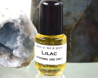 May include: A small glass bottle with a black cap filled with a yellow liquid. The label reads "Objets d'Art & Spirit Lilac EXTERNAL USE ONLY".