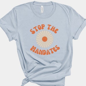 May include: Light blue t-shirt with a retro-style daisy and the text "Stop the Mandates" in orange.