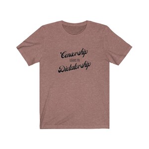 May include: A heather brown t-shirt with the text "Censorship Leads to Dictatorship" printed in black.
