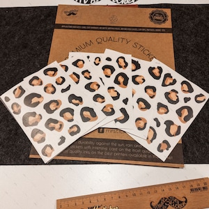 May include: Four sheets of leopard print stickers with brown and black spots on a white background. The stickers are on a brown paper background with the text "Premium Quality Stickers" and "Made by Mr. Sticker" in black text.