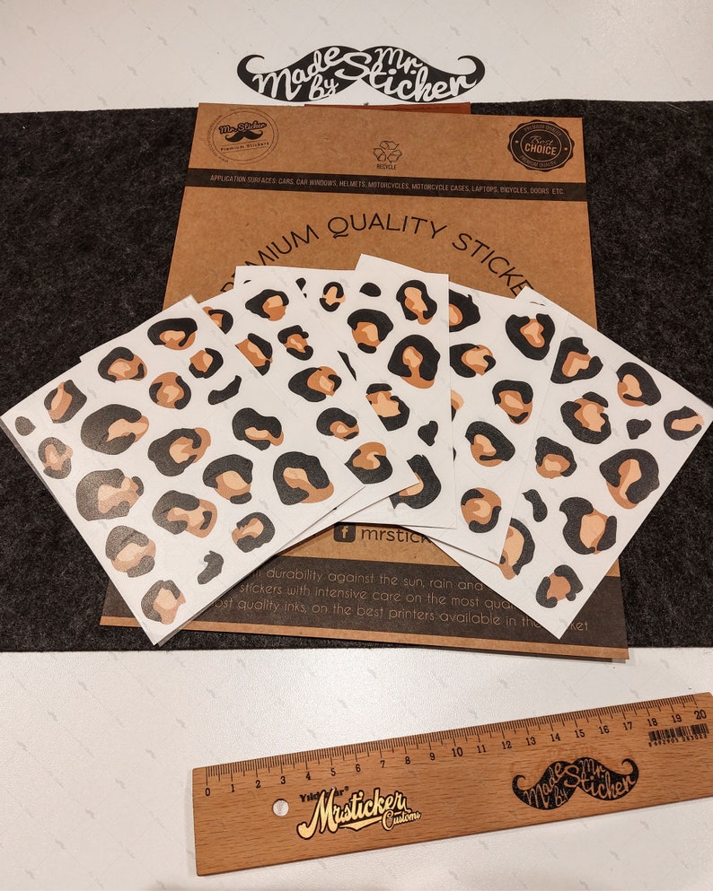 May include: Four sheets of leopard print stickers with brown and black spots on a white background. The stickers are on a brown paper background with the text "Premium Quality Stickers" and "Made by Mr. Sticker" in black text.