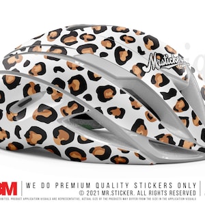 May include: A white bicycle helmet with a brown and black leopard print design. The helmet has the text "Misticker Originals" on the side.