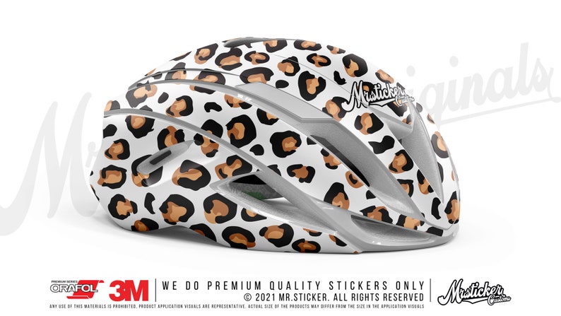 May include: A white bicycle helmet with a brown and black leopard print design. The helmet has the text "Misticker Originals" on the side.