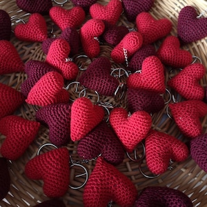 May include: A basket filled with crocheted heart-shaped keychains in red and burgundy.