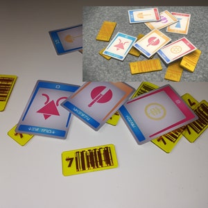 May include: A collection of game cards and tokens. The cards have various geometric designs in pink, blue, and orange, with text in a stylized font. The tokens are yellow with a barcode design and the number 7.