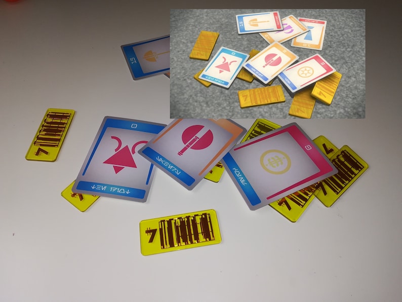 May include: A collection of game cards and tokens. The cards have various geometric designs in pink, blue, and orange, with text in a stylized font. The tokens are yellow with a barcode design and the number 7.