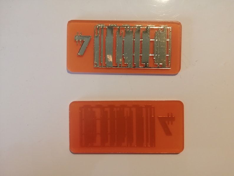 May include: Two orange rectangular objects with silver metal detailing. One has the number 7 and a series of vertical lines. The other has a mirrored image of the lines and the number 7.