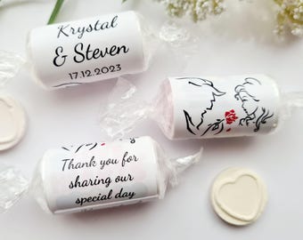 May include: White favor boxes with black text and a design of Belle and the Beast from Beauty and the Beast. The boxes say "Thank you for sharing our special day" and "Krystal & Steven 17.12.2023".