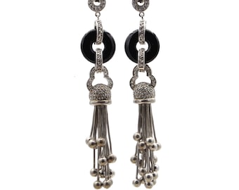 May include: A pair of silver dangle earrings with black onyx stones and a tassel design. The earrings are adorned with clear cubic zirconia stones.