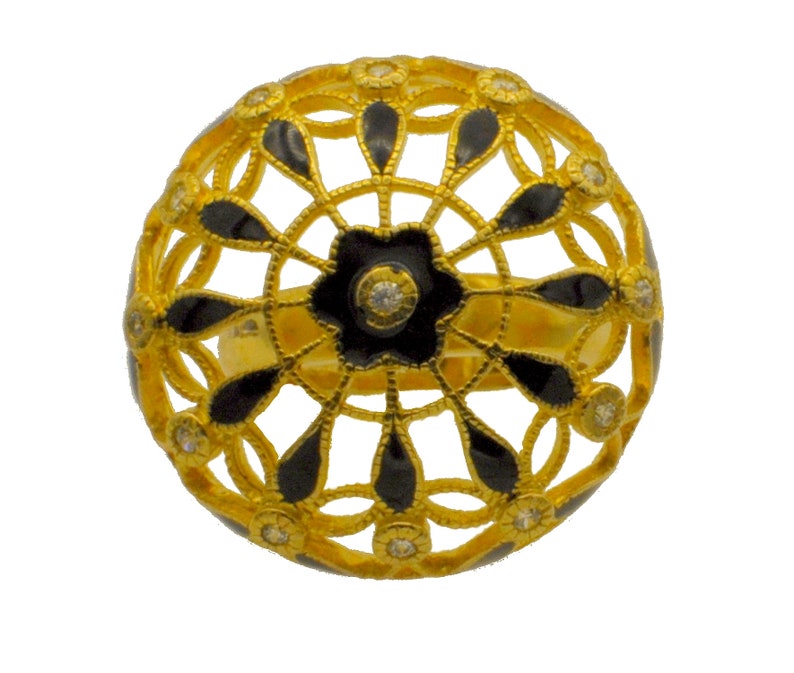May include: A gold ring with a black enamel design. The ring is shaped like a sphere and has a delicate, intricate pattern. The design features small, clear stones.
