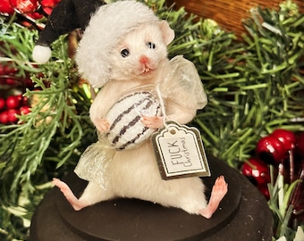 May include: A white mouse figure wearing a Santa hat and holding a wrapped candy. The candy has white and black stripes. A tag with the text "FUCK Christmas" hangs from the candy. The mouse is on a black base, surrounded by festive greenery and red berries.