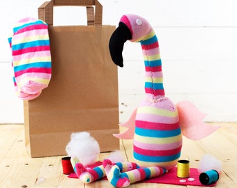 May include: A pink and blue striped sock flamingo craft project with a brown paper bag, pink and blue striped socks, white stuffing, and spools of thread.